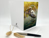 Cropped photo of a greeting card featuring an Egret displayed with an envelope and props.
