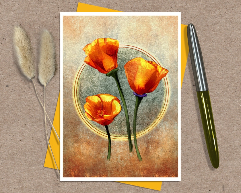 A greeting card featuring three orange poppy flowers on a textured beige and brown background, styled on a kraft paper surface with a yellow envelope, dried bunny tail grass, and a metallic pen.
