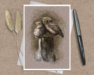Product photo of a bird greeting card in brown featuring two burrowing pygmy owls on a stump.