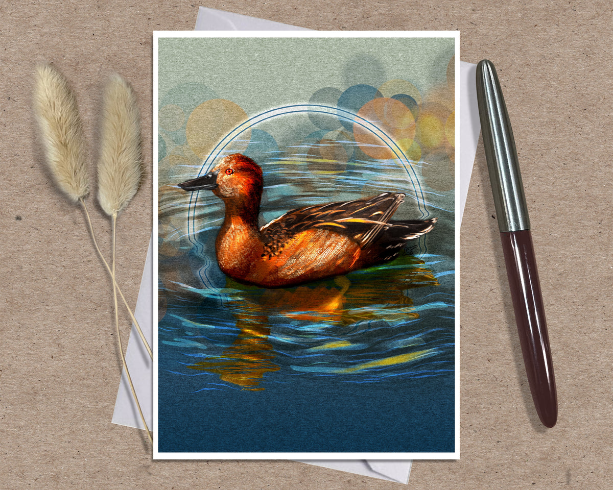 A greeting card featuring a detailed illustration of a red-breasted duck on blue water, styled on a brown textured background with a silver pen and dried grass stems.
