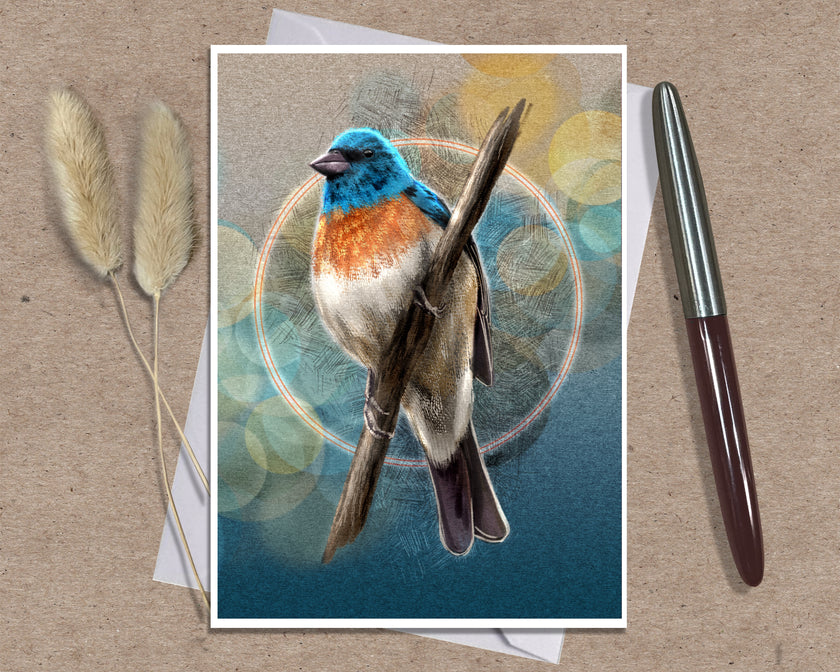 A art print greeting card featuring a detailed illustration of a bluebird perched on a branch, set against a bokeh background. The print is styled on a textured kraft paper background alongside a silver and brown pen and two dried bunny tail grasses.