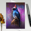 Greeting card with a blue bird wearing a party hat on a purple background, next to a pen and decorative elements.