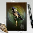 Greeting card with a bird illustration and humorous text, placed on a surface with a pen and shell.