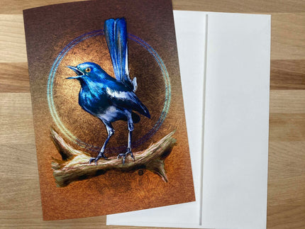 Greeting card with a blue bird illustration on a wooden surface