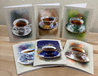 Set of greeting cards with tea cup illustrations on a wooden surface