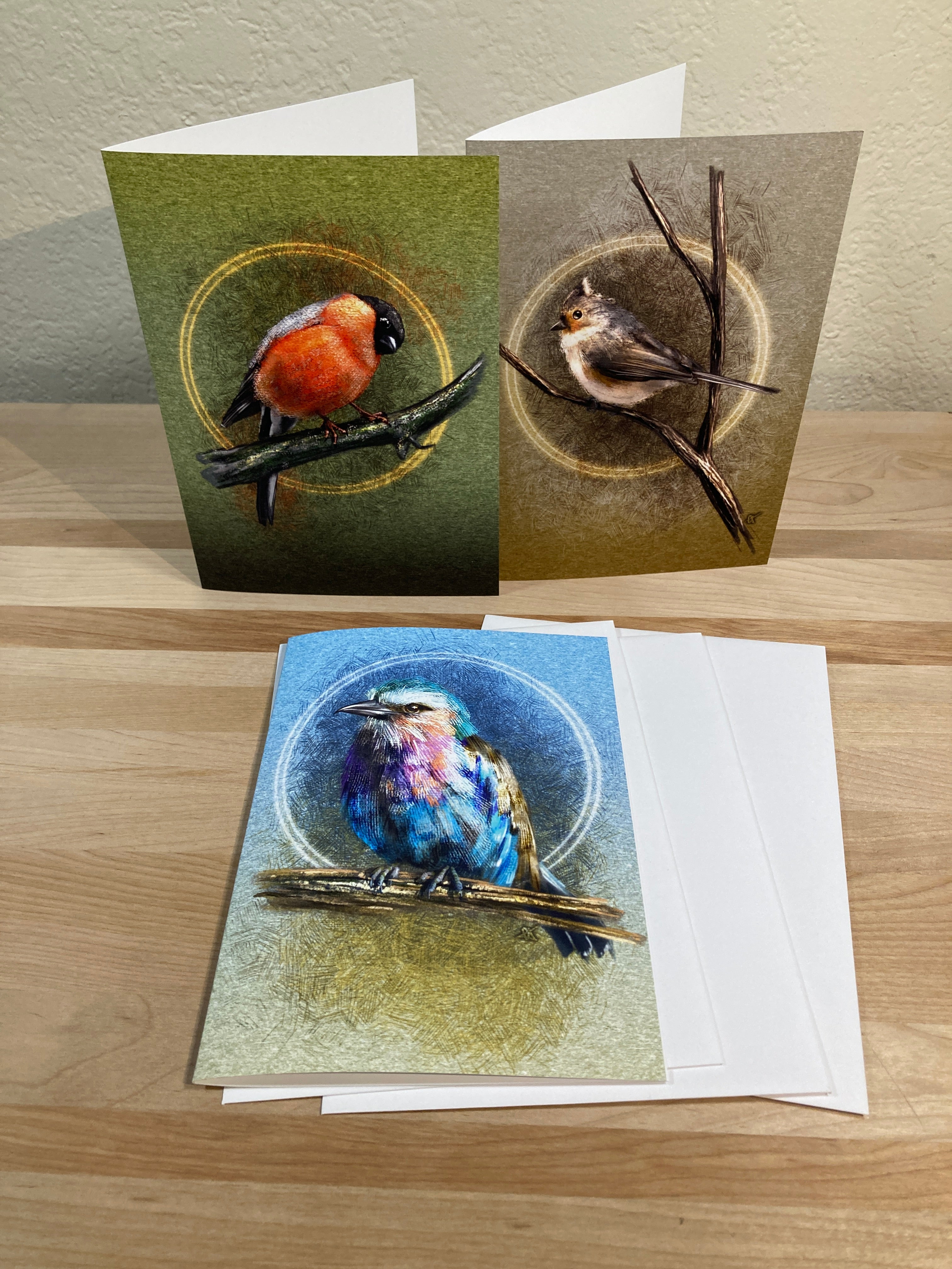 Three greeting cards with nature-themed designs on a wooden surface