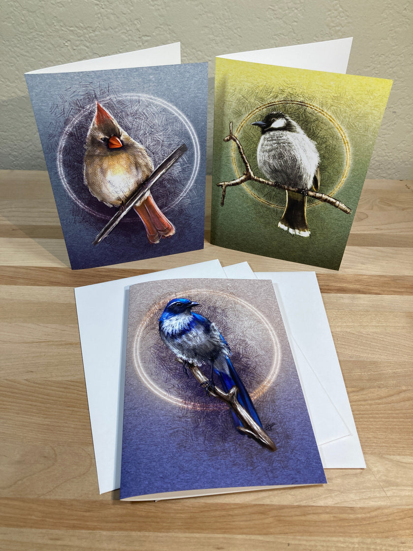 Three greeting cards with bird illustrations on a wooden surface