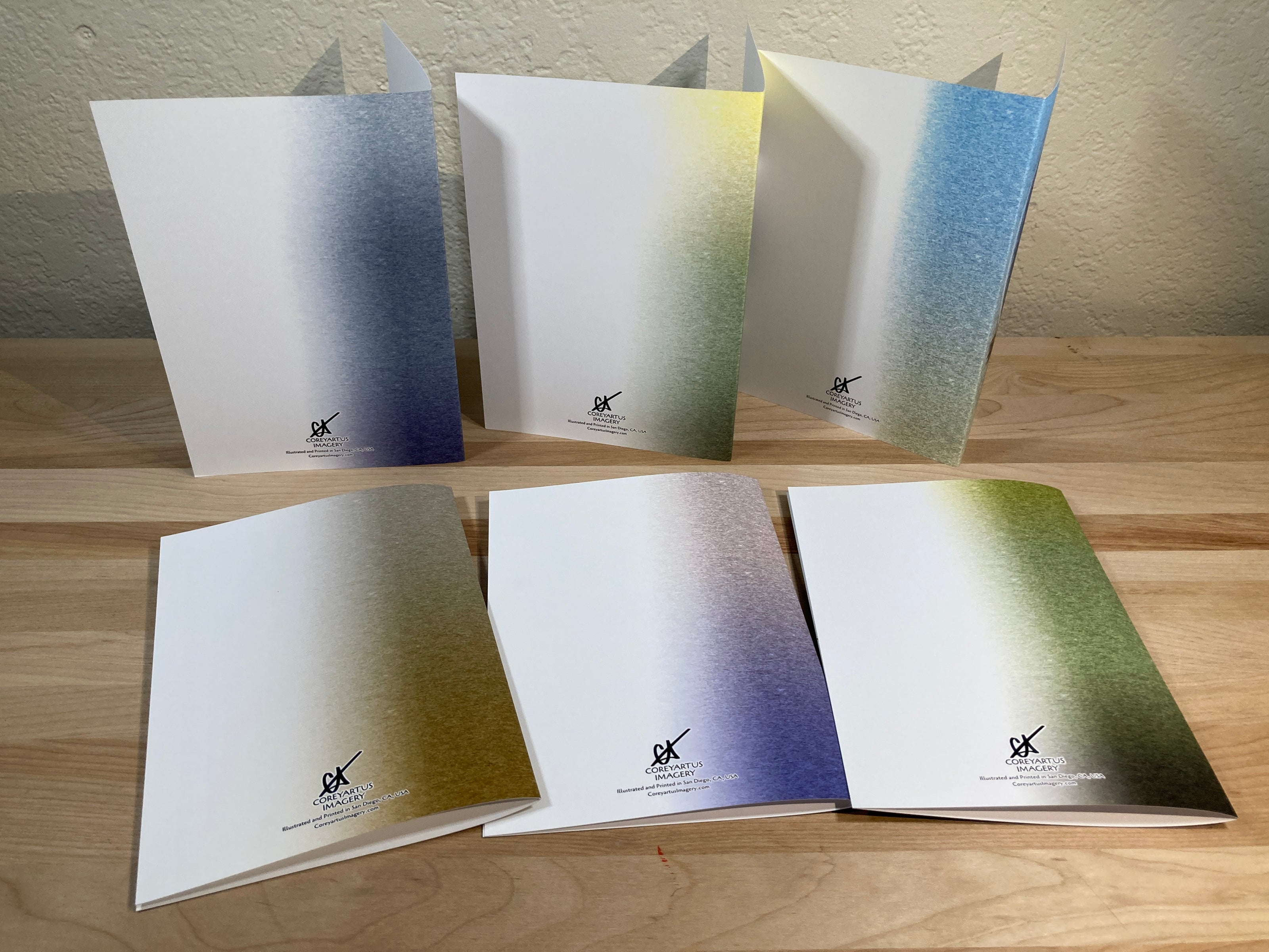 Set of gradient notebooks with a brand logo on a wooden surface