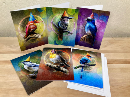 Set of greeting cards with colorful bird illustrations on a wooden surface.