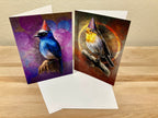 Two greeting cards with bird illustrations wearing party hats on a wooden surface.