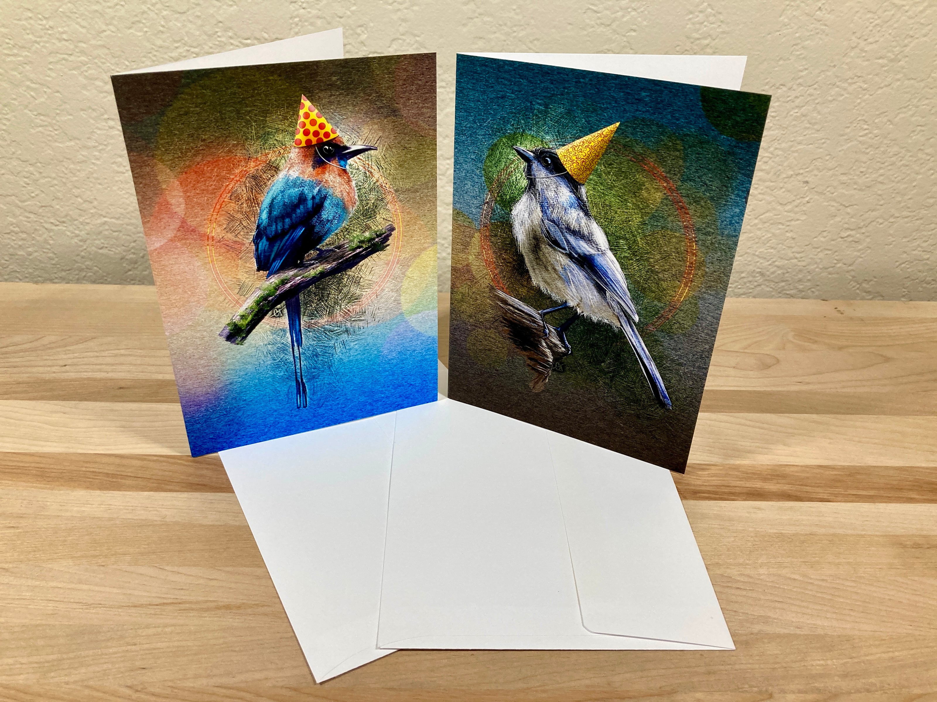 Two greeting cards with bird illustrations on a wooden surface