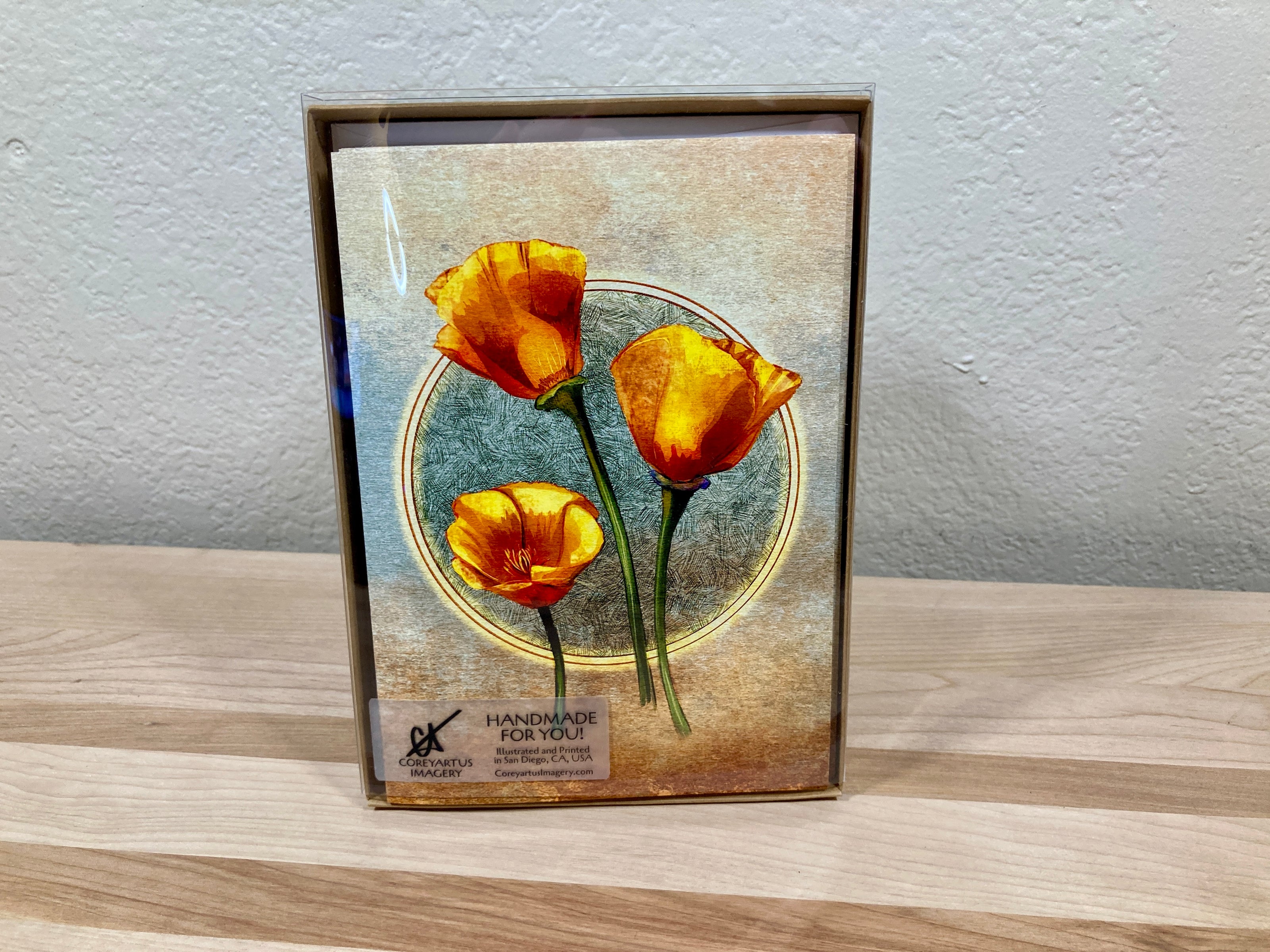Greeting card pack in case, with orange flowers on a wooden surface