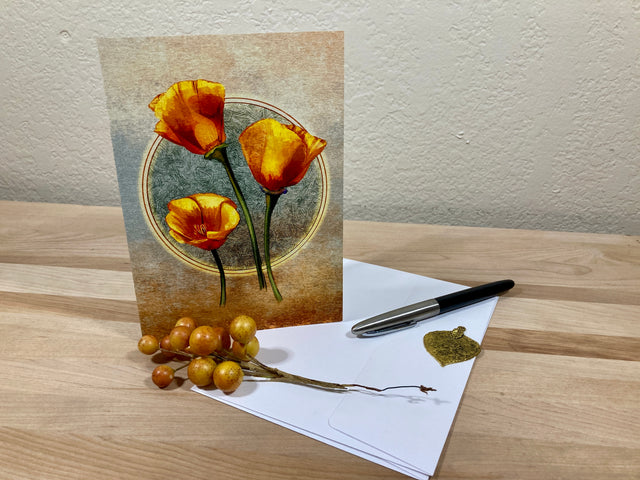 Greeting card with orange flowers on a wooden surface with a pen and envelope.