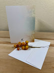 Greeting card with envelope and decorative branch on a wooden surface