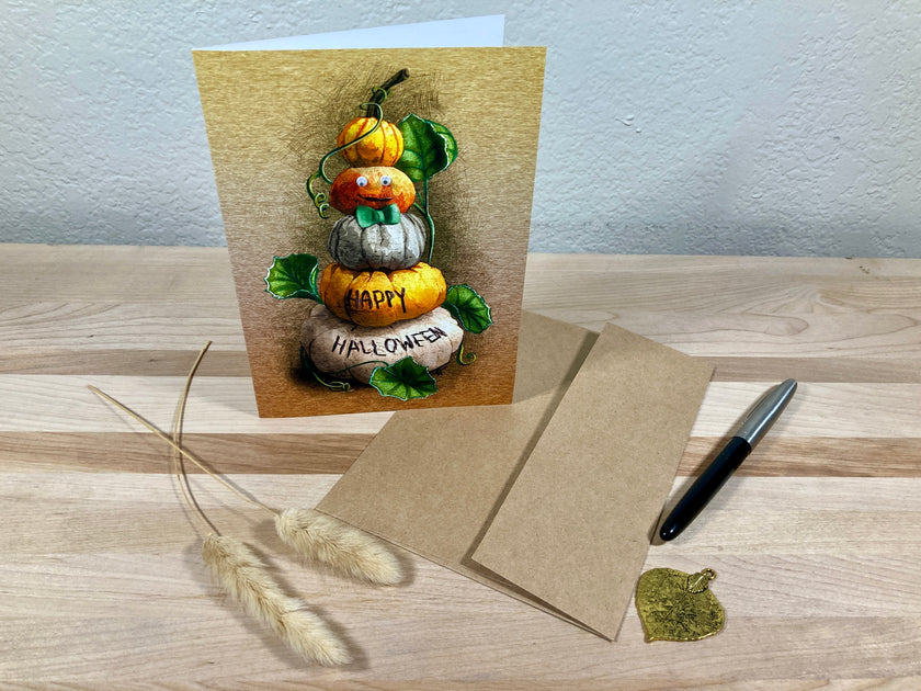 Halloween-themed greeting card with pumpkins and a pen on a wooden surface