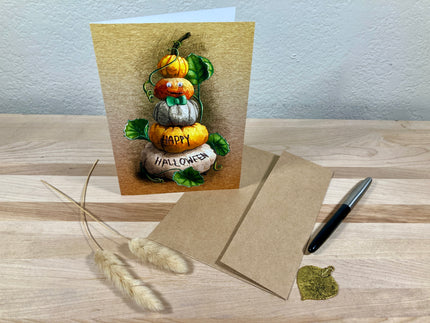 Halloween-themed greeting card with pumpkins and a pen on a wooden surface