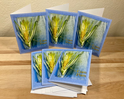 Set of greeting cards with corn illustrations on a wooden surface