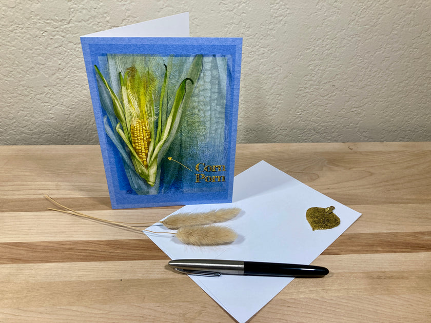 Greeting card with corn plant design on a wooden surface with a pen and paper.