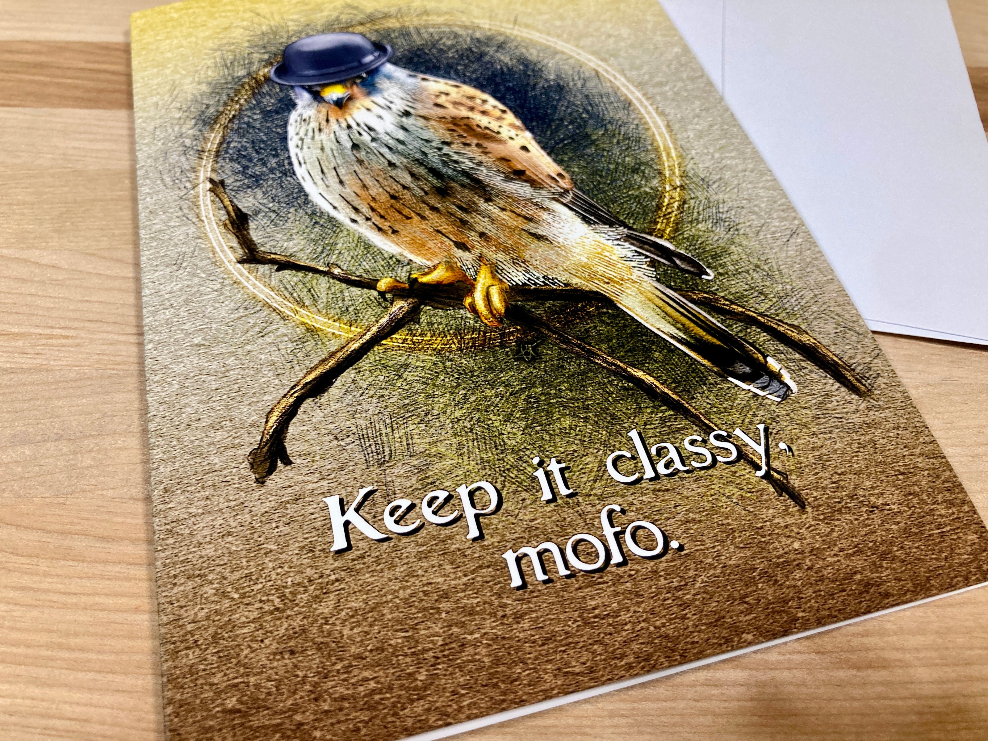 Greeting card with a bird illustration and text 'Keep it classy. mofo.' on a wooden surface.