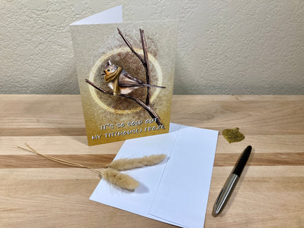 Greeting card with a bird design on a wooden surface with a pen and envelope.