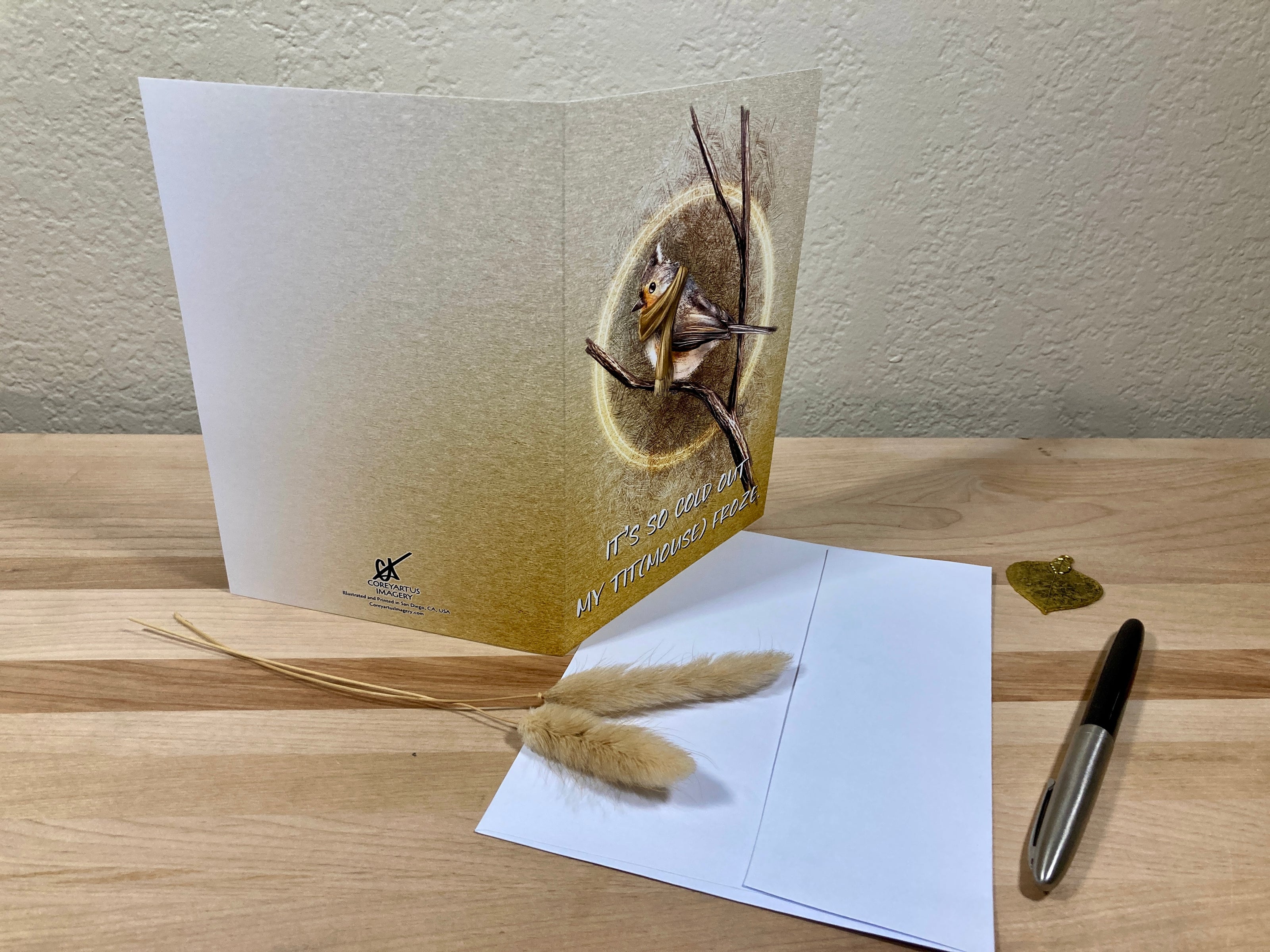 Greeting card with nature-themed design on a wooden surface with a pen and decorative elements.