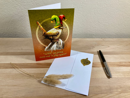 Greeting card with a witch and broom design on a wooden surface with an envelope and pen.
