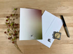 Back of a greeting card with a pen,and decorative items on a wooden surface