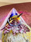 Hummingbird with a purple cone-shaped hat on a textured surface