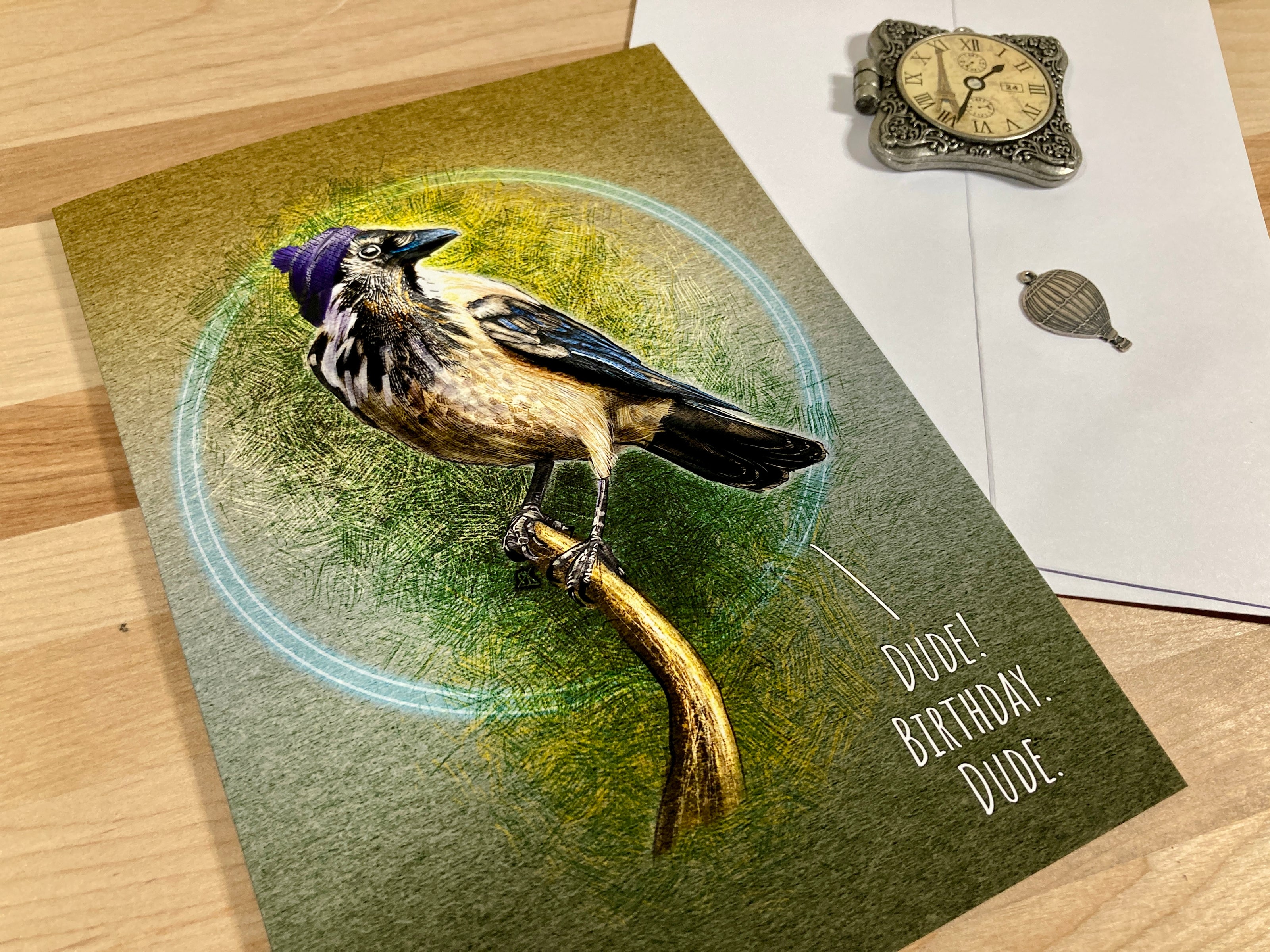 Greeting card with a bird illustration and 'Happy Birthday, Dude' text on a wooden surface.