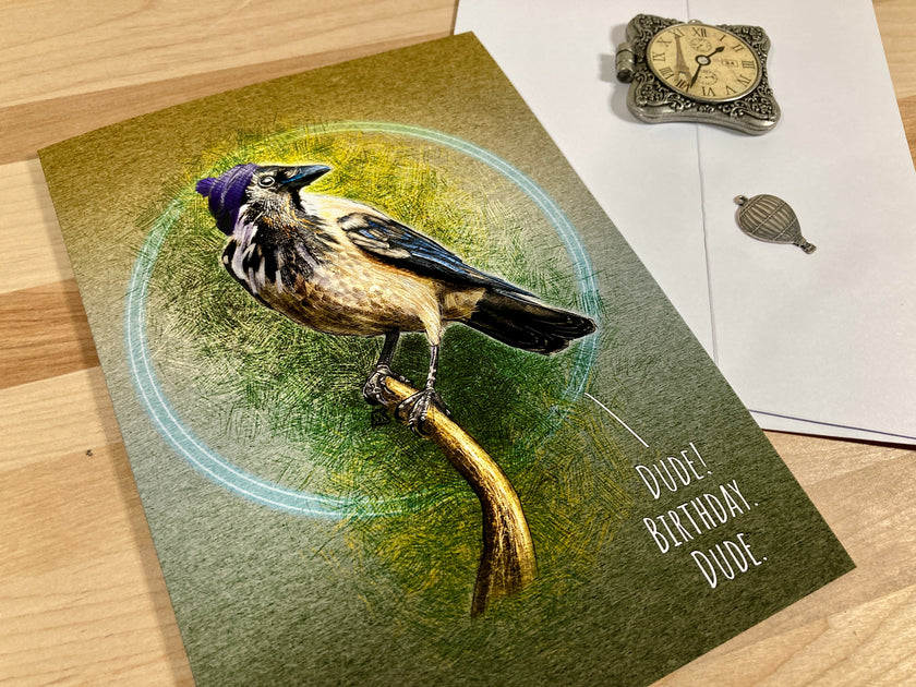 Greeting card with a bird illustration and 'Happy Birthday, Dude' text on a wooden surface.