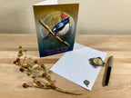 Birthday card with a bird design on a wooden surface with an envelope and decorative items.