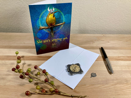 Greeting card with a bird design on a wooden surface with an envelope and decorative elements.