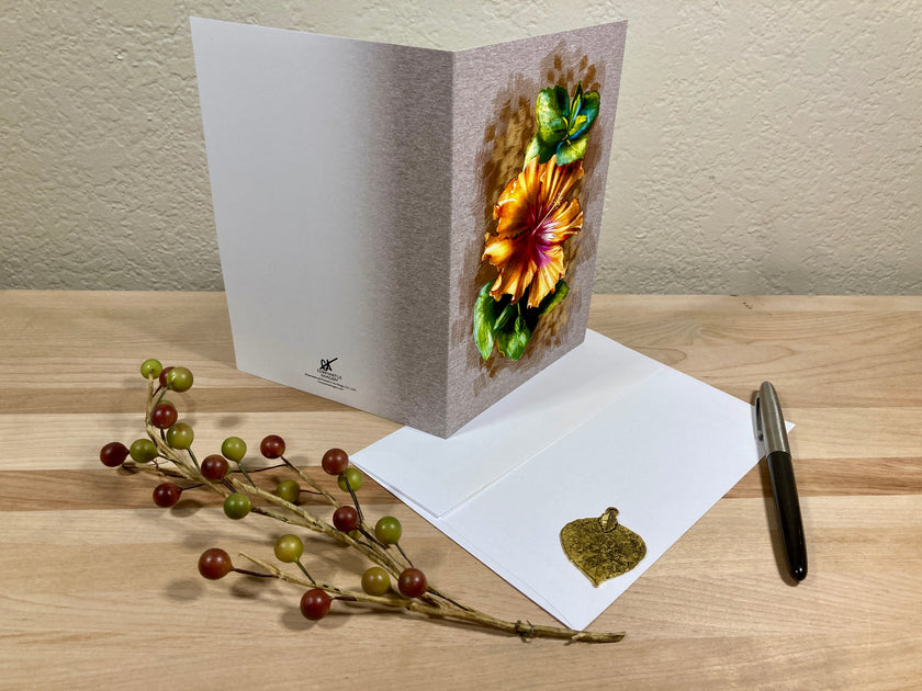 Greeting card with floral design on a wooden surface with a pen and decorative branch.