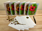 Set of floral greeting cards with envelopes and a pen on a wooden surface