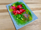 Painting of a red flower on textured paper with a wooden surface background