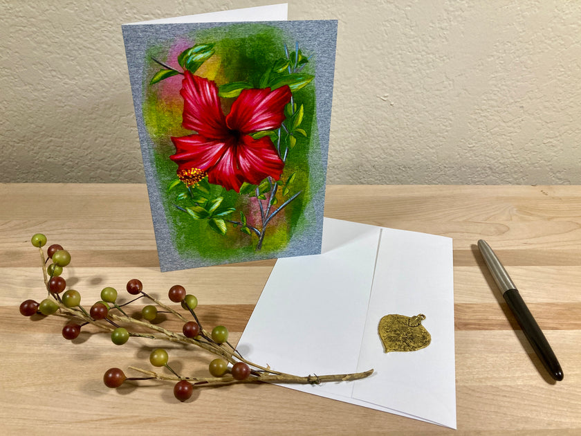 Floral greeting card with red flower, pen, and envelope on a wooden surface