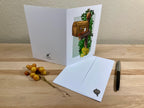 Greeting card with mailbox illustration on a wooden surface with envelope and decorative elements.