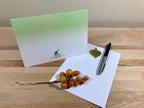 Greeting card with a pen and decorative branch on a wooden surface