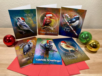 Set of Christmas cards with bird illustrations on a wooden surface with decorative balls.