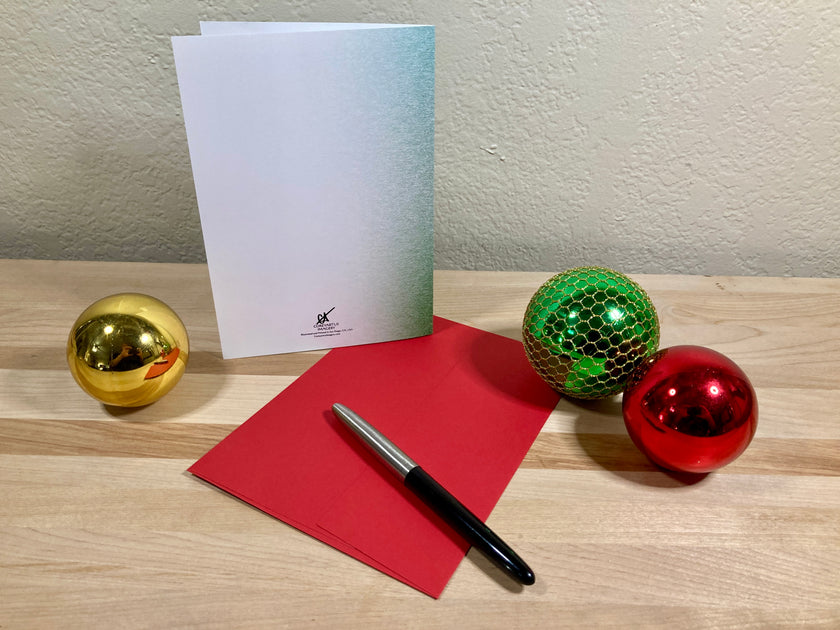 Decorative items including a gold ball, green disco ball, red ball, red card, and pen on a wooden surface.