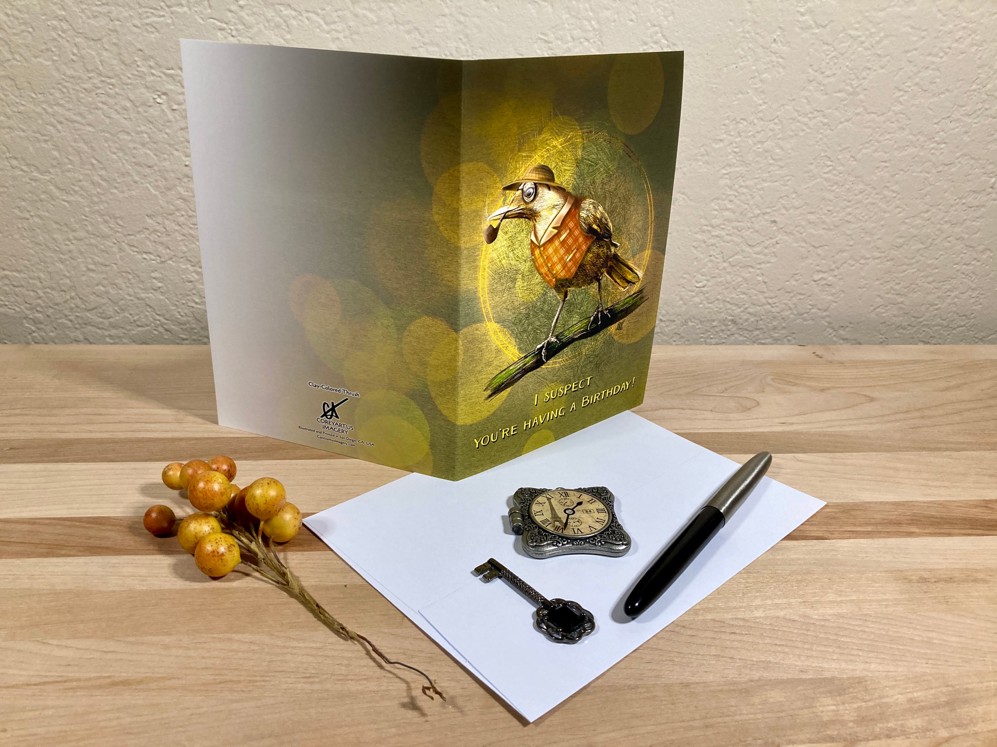 Greeting card with a bird illustration on a wooden surface with stationery items.