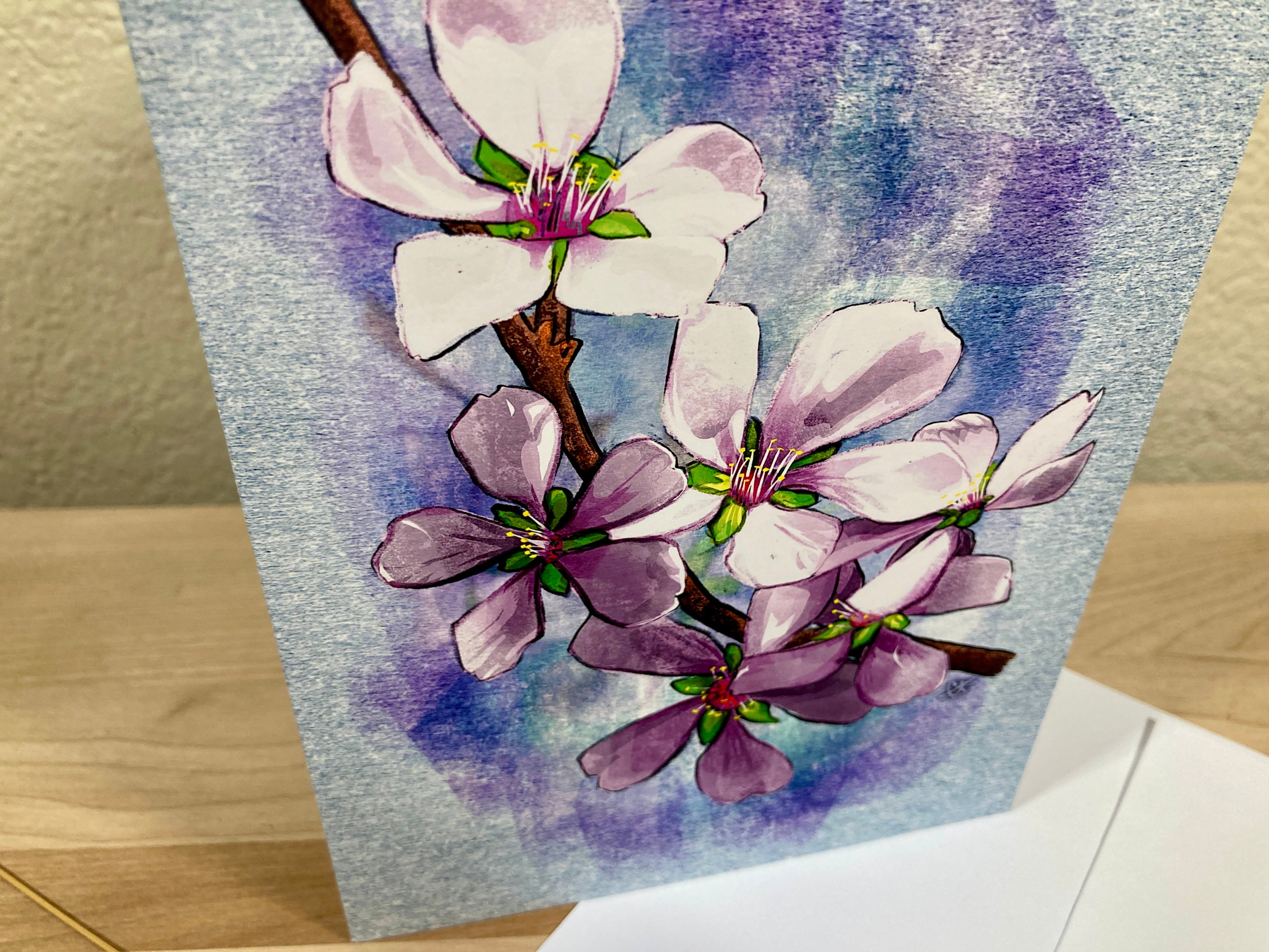 Card with watercolor illustration of pink flowers on a blue background