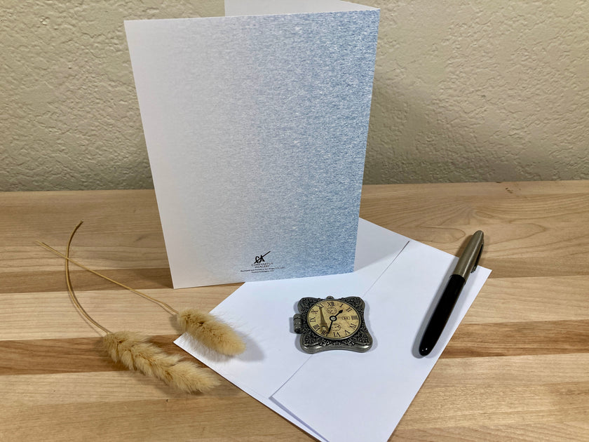 Greeting card with envelope, pen, and decorative item on a wooden surface