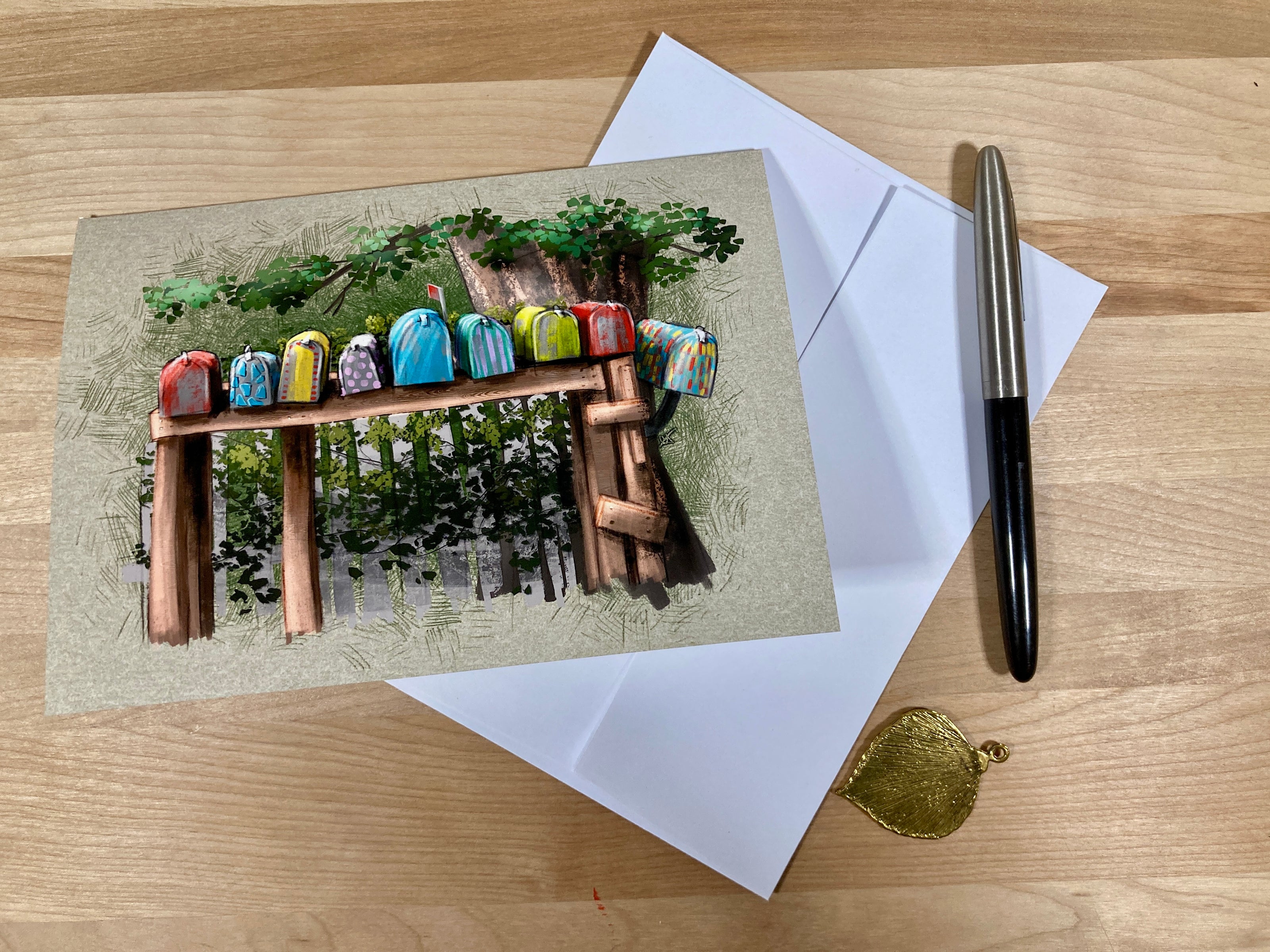 Greeting card with colorful birdhouses on a wooden bench, envelope, pen, and gold seal on a wooden surface.