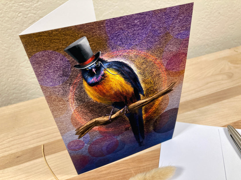 Greeting card with a colorful bird wearing a top hat on a wooden surface.