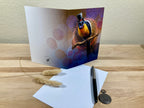 Greeting card with a bird illustration on a wooden surface with an envelope and pen.