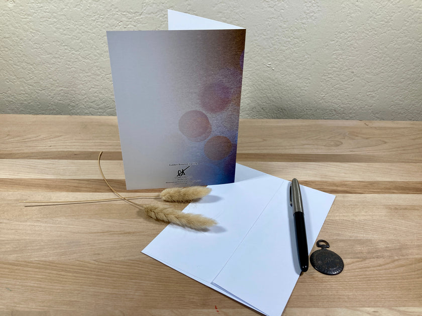 Greeting card, pen, and decorative elements on a wooden surface