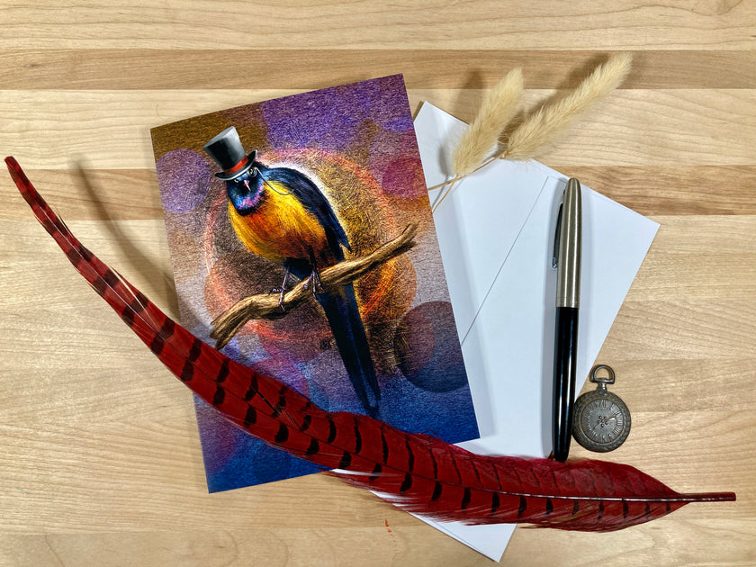 Greeting card with a bird design, envelope, pen, and feather on a wooden surface