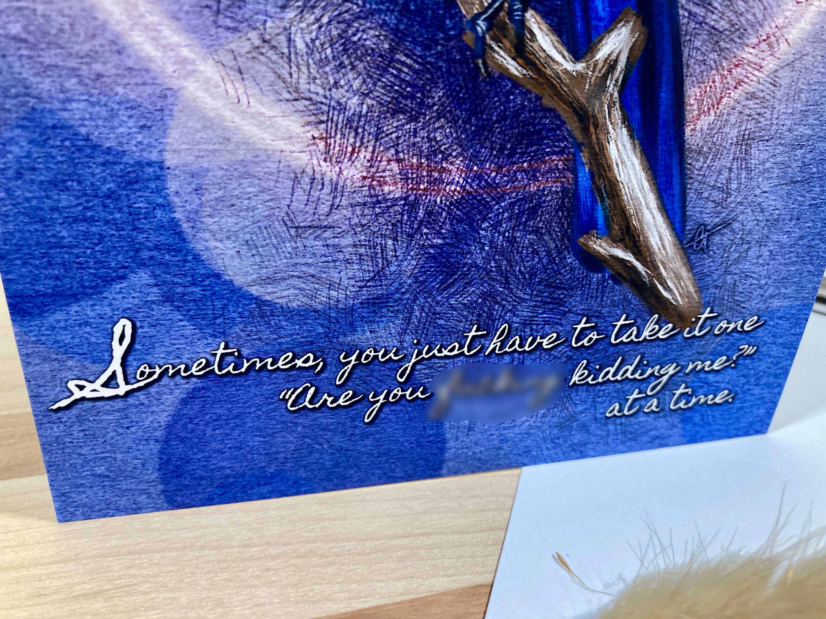 Blue card with silver branch and text on a wooden surface