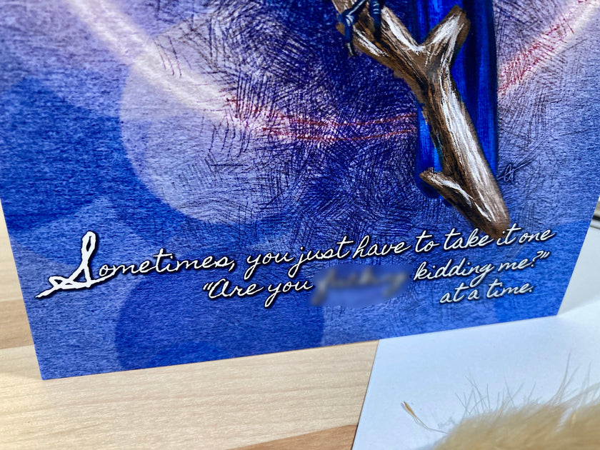 Blue card with silver branch and text on a wooden surface